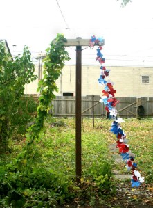 "American 2012 (Pyramid Without a Capstone)", 2012, Found paper images, wooden laundry pole, cascade hops vine, aluminum wire, and nylon string, sizes variable