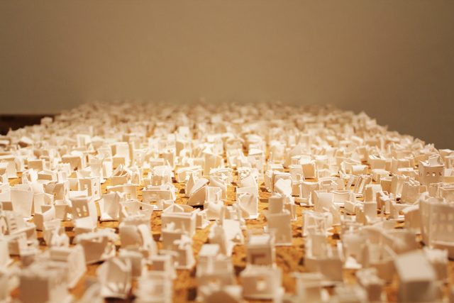 Title:  ‘Illusions of Stability’ Medium: Porcelain, Wood Size: Total dimension: 3.5 feet x 4.5 feet. Each house: various size range: ¾ inch- 2/4 inch Year: 2014 